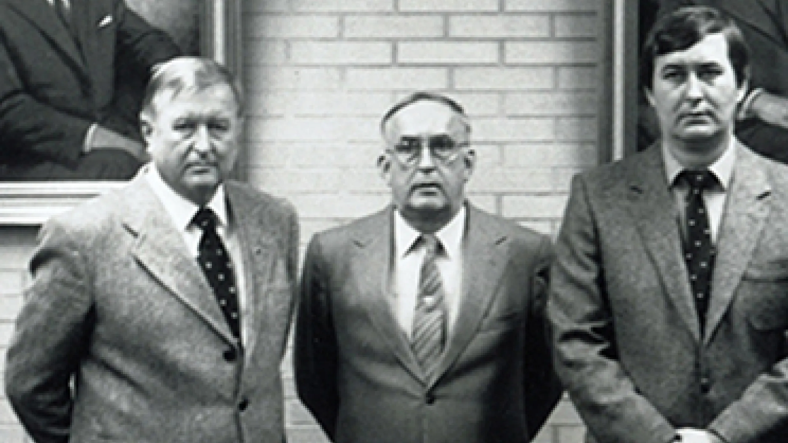 Drei Geschäftsführer in dritter Generation der Reich GmbH stehen mit Blick in die Kamera vor einer Wand mit Portraits.