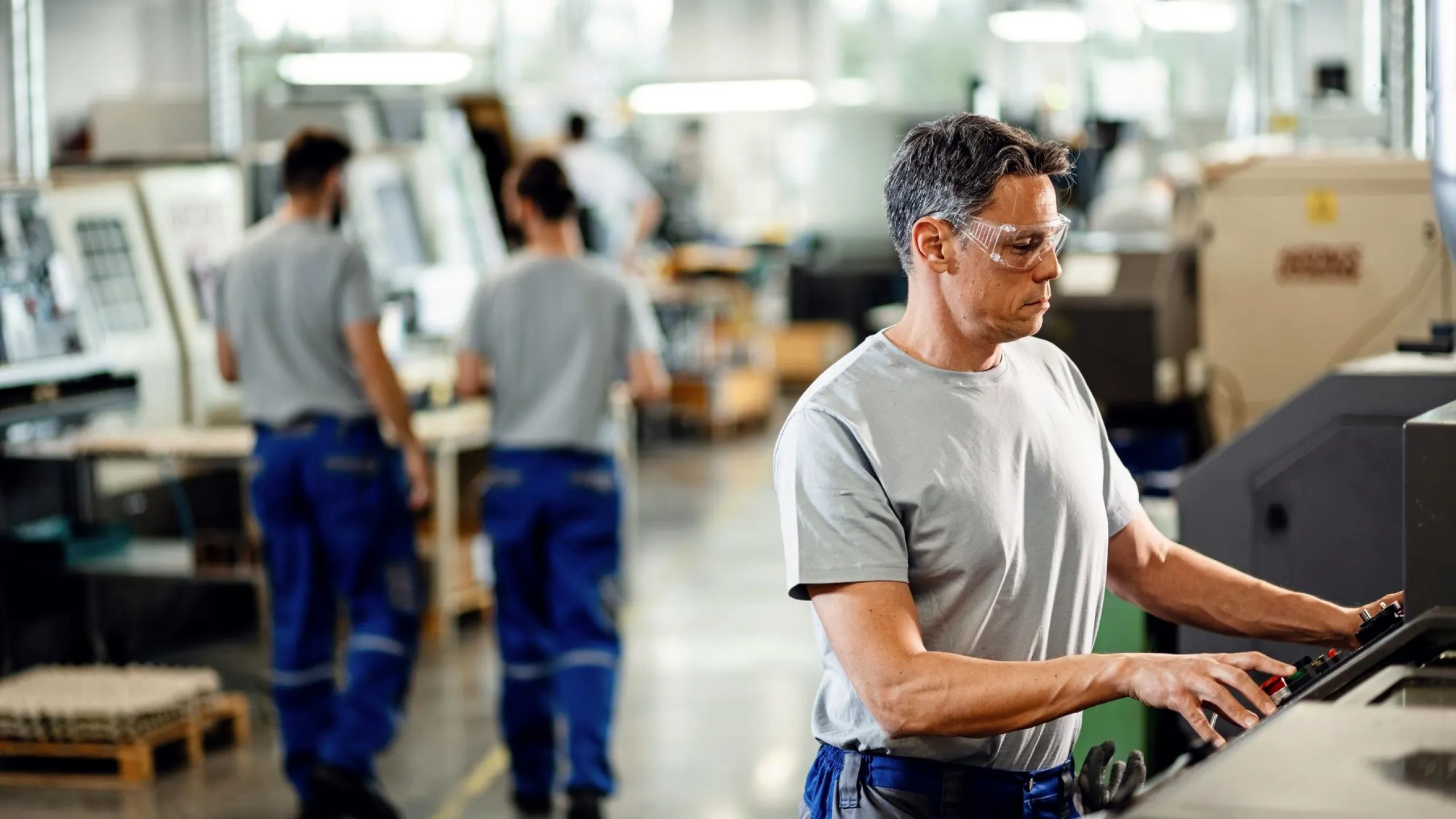 Arbeiter der eine CNC Maschine bedient.
