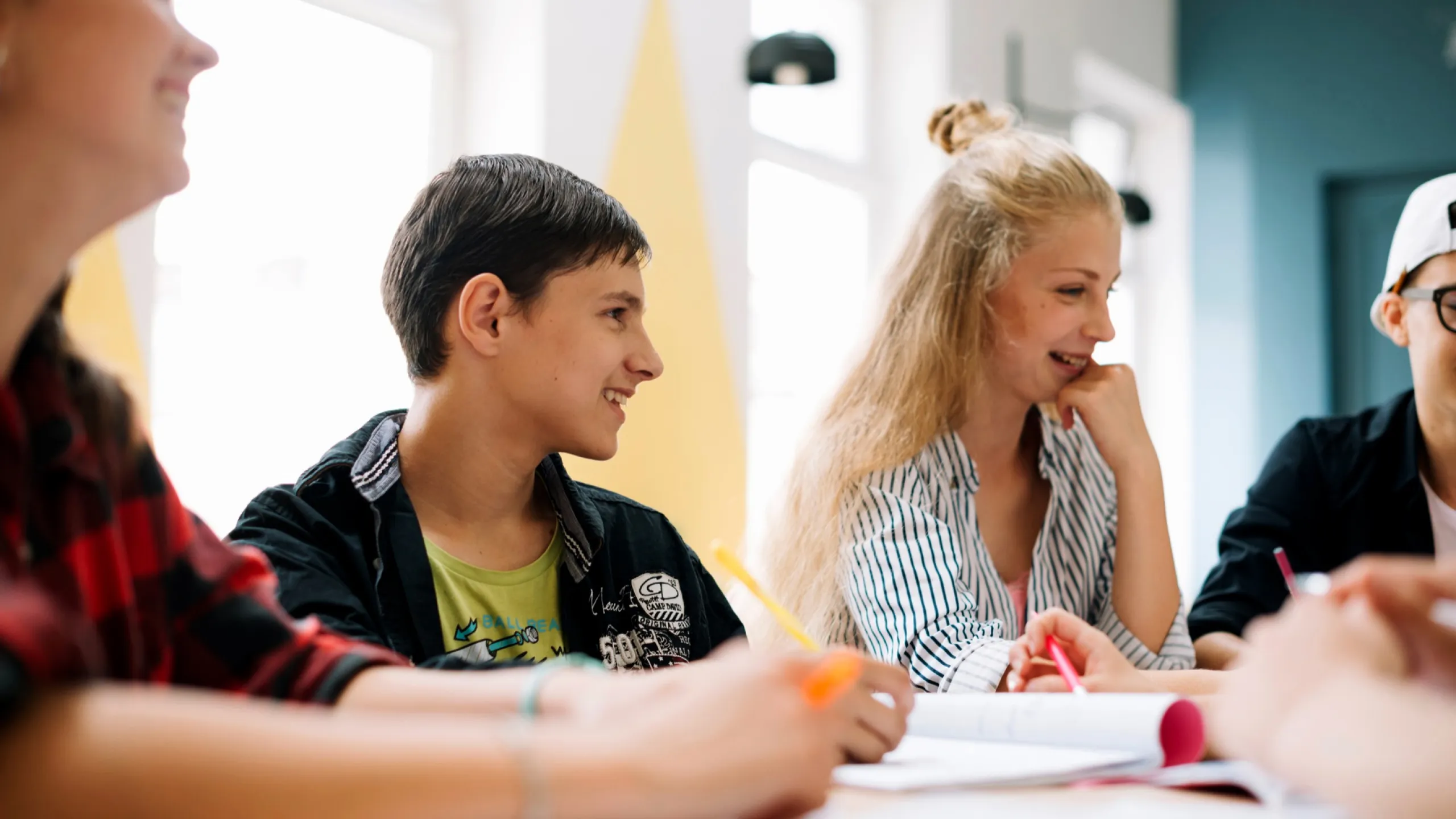 Vier Schüler die an einem Tisch sitzen und lachen.