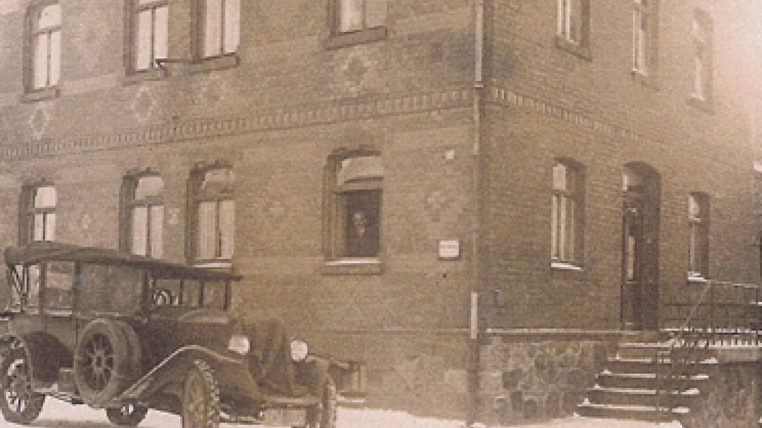 Altes Haus vor welchem ein altes Auto parkt.