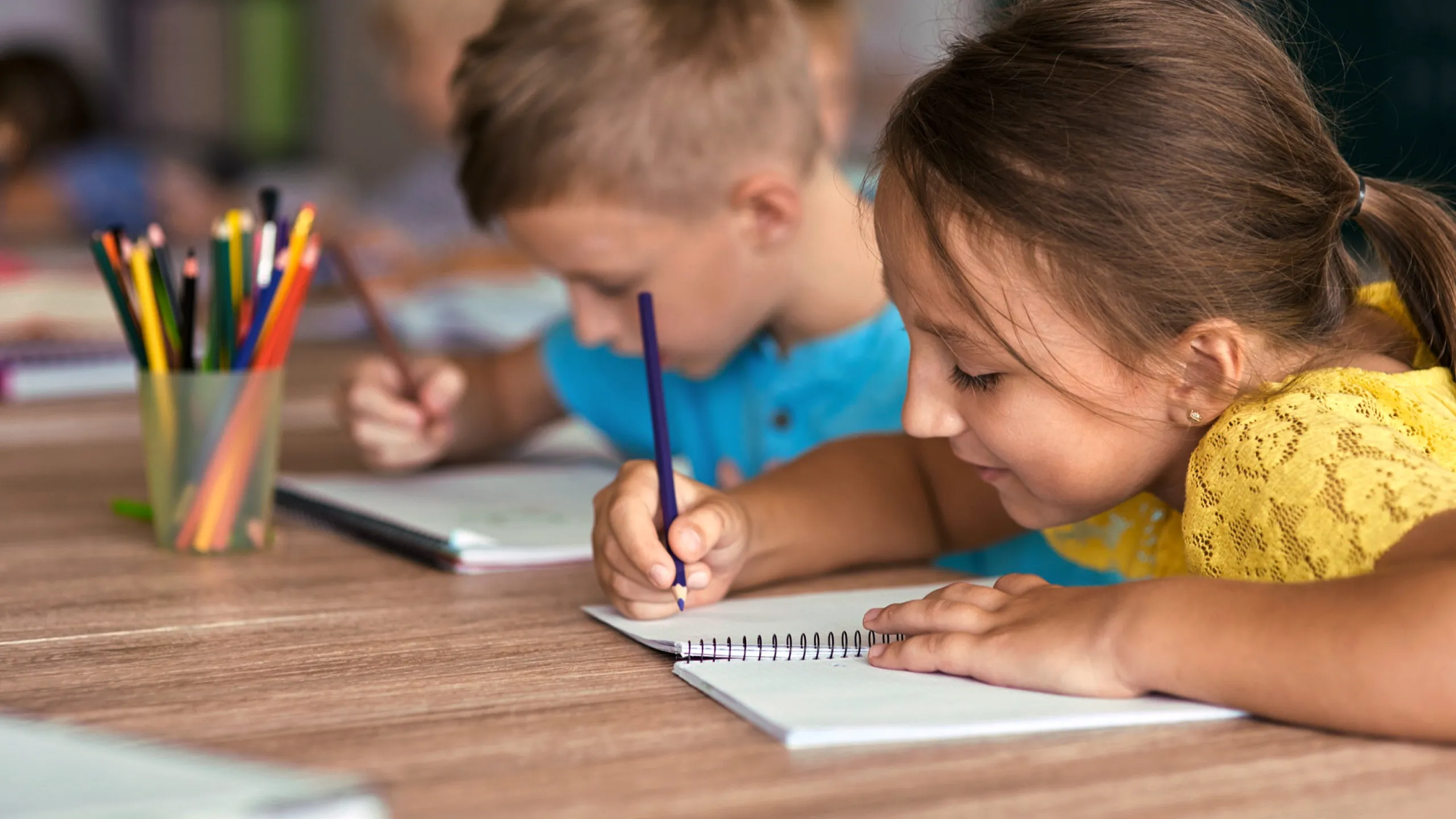 Zwei Schüler sitzen an einem Tisch und schreiben.