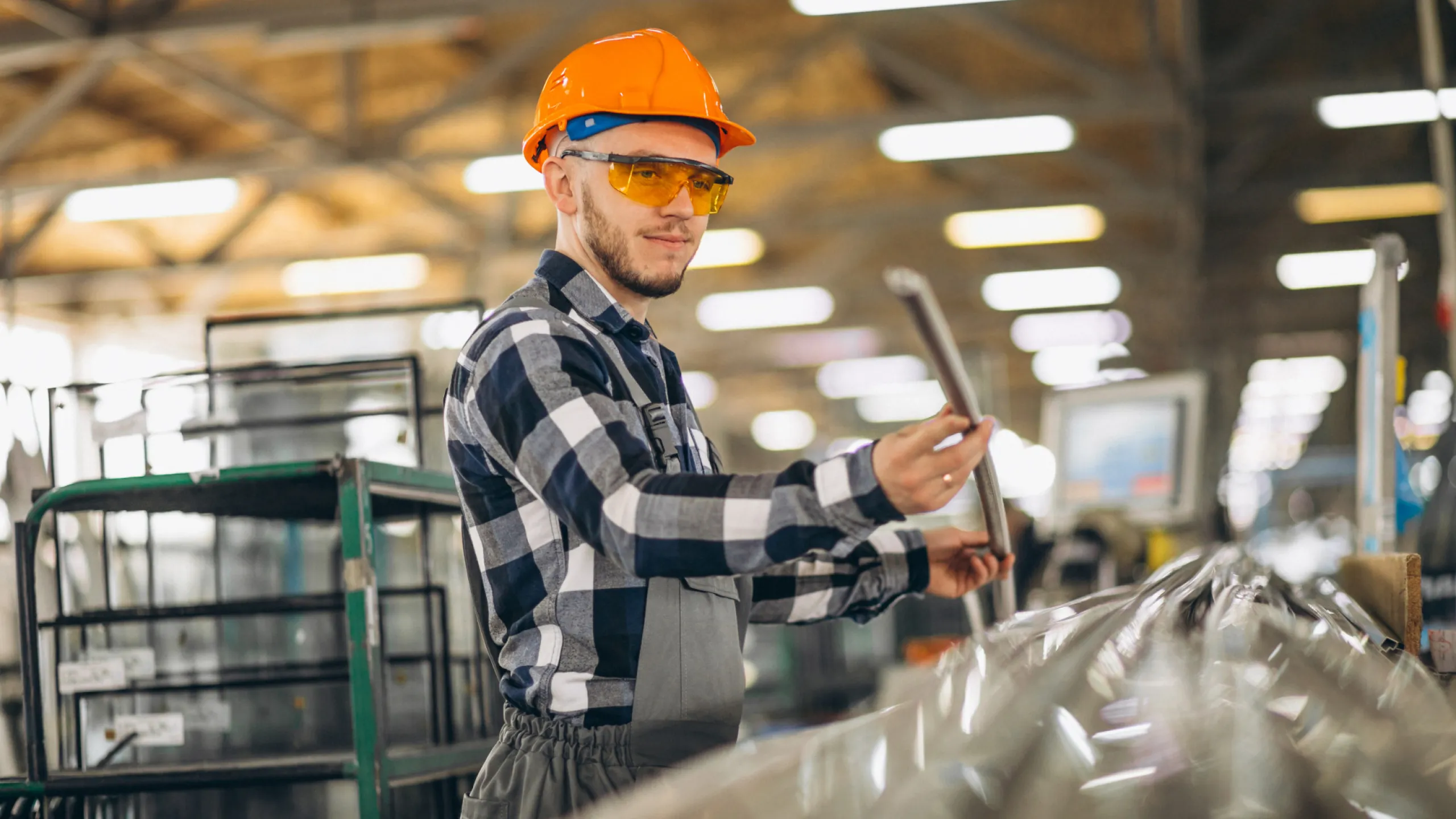 Arbeiter mit Metallstange in der Hand in einem Produktionsgebäude.