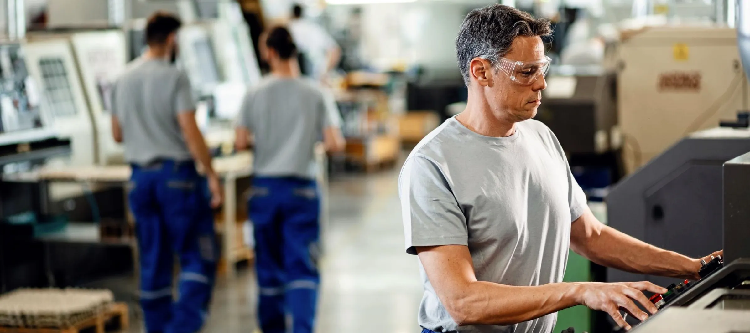 Arbeiter der eine CNC Maschine bedient.