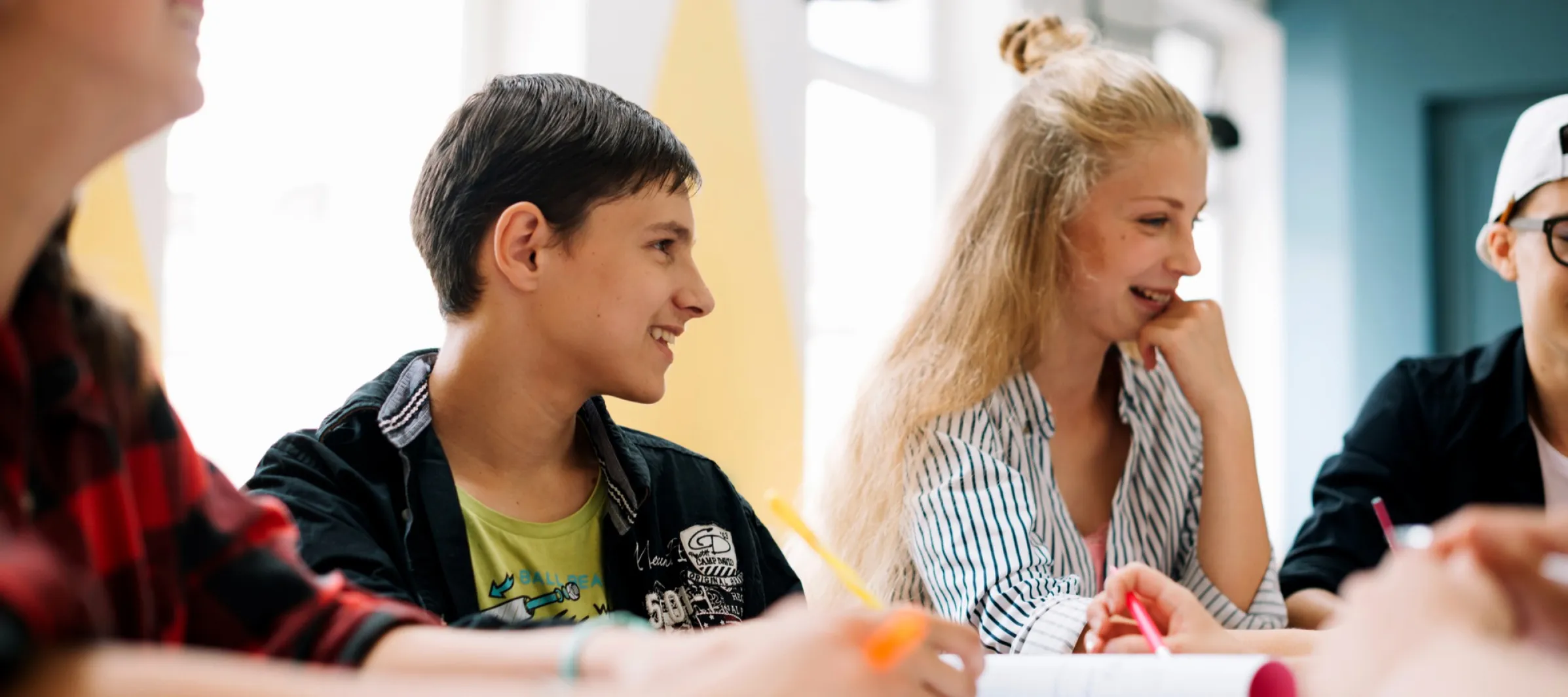Vier Schüler die an einem Tisch sitzen und lachen.