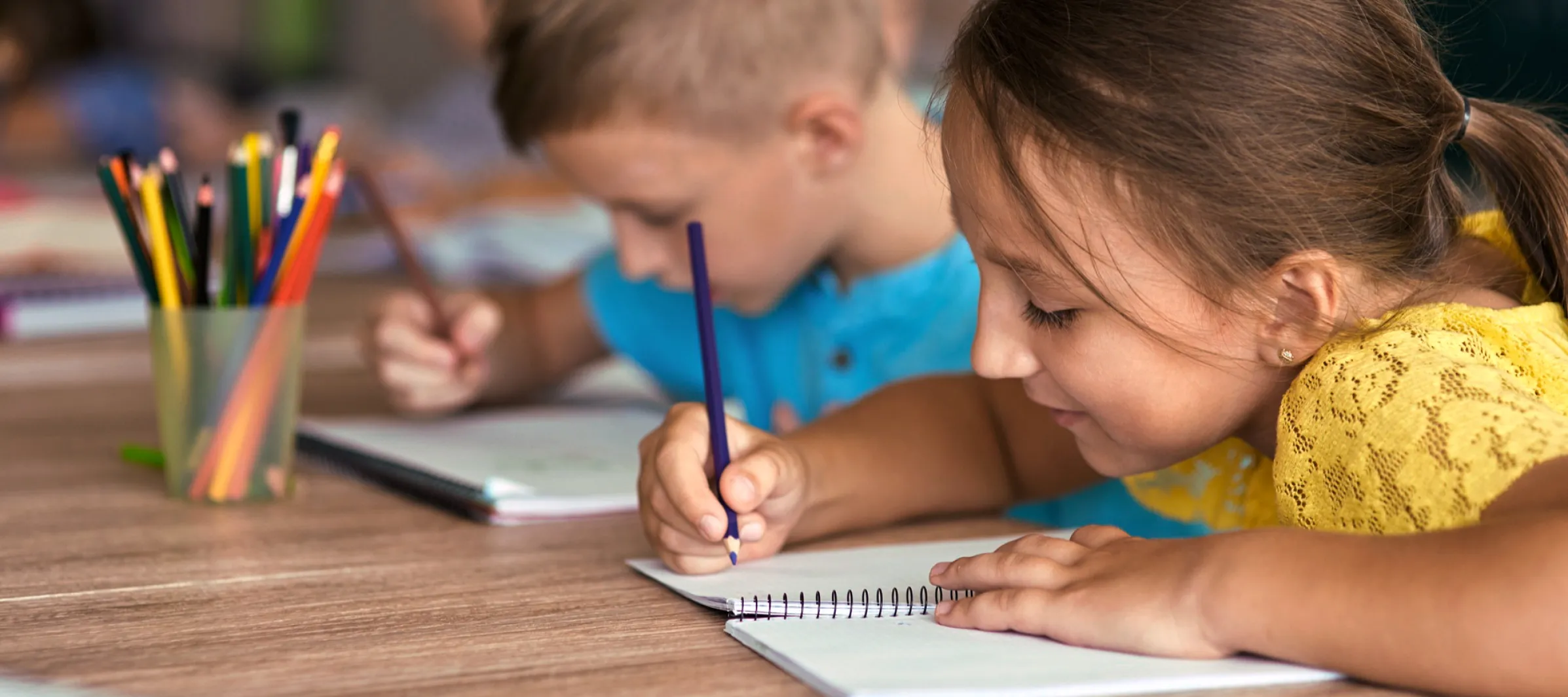 Zwei Schüler sitzen an einem Tisch und schreiben.